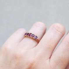 Cool magenta rubies are set in swirling filigree in this antique gold ring. The cushion shape of the stones pop from the carved band and tiny diamonds bookend each end. Originating from England in 1890, this bold ring is one of a kind. Stones: Five Rubies, Total 1.50tcw, Small White DiamondsMetal: 18k Yellow GoldMeasurements: Setting length: 13.7mm, Setting width: 5.1mm, Setting height: 4.3mm, Band width: 2.3-1.8mmWeight: 3g Size 6.5 in stock Shipping and Delivery: IN STOCK items will ship within 2 business days Sizes not In Stock will be Resized Resize Fee may apply Please allow 2 weeks for delivery All Resize items are final sale Please make sure to have your correct ring size before ordering Prices may vary by variant Antique Ruby Ring With Single Cut Diamonds, Ruby Ring With Diamond Cut Round Band, Ruby Ring With Diamond Cut, Oval Ruby Ring With Intricate Design, Fine Jewelry Red Ruby Ring With Intricate Design, Antique Ruby Rings With Single Cut Diamonds, Vintage Ruby Rings With Single Cut Diamonds, Oval Ruby Rings With Single Cut Diamonds, Antique Ruby Filigree Ring With Gemstone