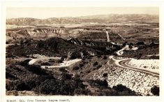 an old photo of a road winding through the hills in california, with mountains and fields behind it