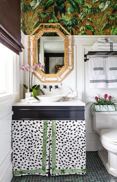 a bathroom with green and white decor on the walls, toilet, sink and mirror