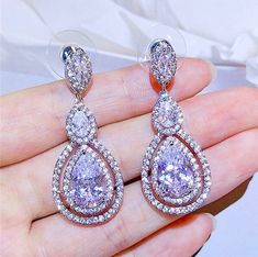 A delightfully unique pair of bridal earrings with an incredible sparkle! Adorned with flawlessly faceted cubic zirconia that capture the light in a dazzling array of sparkles, the earrings are rhodium plated for a bright finish which enhances the intricate detailing and conveys a modern take on old elegance. Overall length of the earring is 1.5" (approx. 4cm). Available in Silver, Rose Gold and Yellow Gold finishes. To make your choice select your preferred finish from the dropdown menu to add Dazzling Cubic Zirconia Bridal Earrings, Sparkling Cubic Zirconia Bridal Earrings For Anniversary, Wedding Sparkling Cubic Zirconia Diamond Earrings, Dazzling Diamond White Crystal Bridal Earrings, Dazzling Diamond White Bridal Earrings With Crystal, Teardrop Chandelier Earrings In Cubic Zirconia With Brilliant Cut, Dazzling Cubic Zirconia Dangle Bridal Earrings, Bridal Drop Earrings With Cubic Zirconia Stones, Brilliant Cut Teardrop Chandelier Earrings With Cubic Zirconia