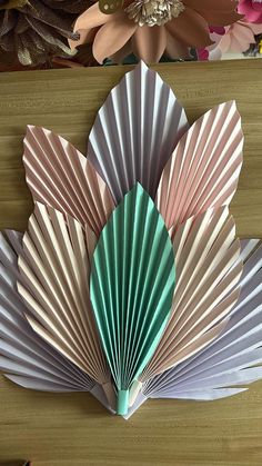 the folded paper fan is sitting on top of a wooden table next to other decorative items