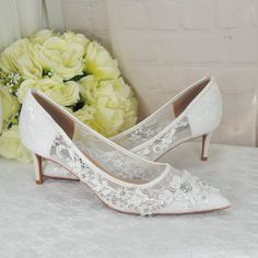 a pair of white shoes sitting on top of a table next to a bouquet of flowers