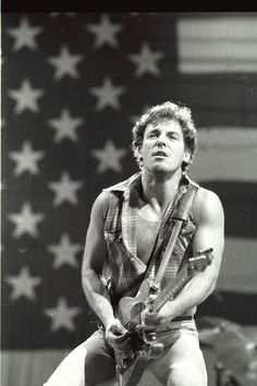 a man holding a guitar in front of an american flag