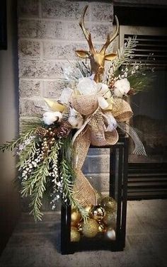 a christmas arrangement in front of a fireplace with gold ornaments and deer antlers on it