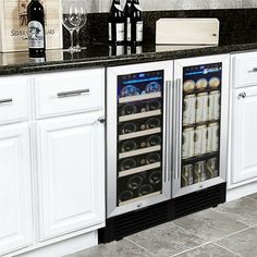 a wine cooler sitting in the middle of a kitchen with white cabinets and black counter tops