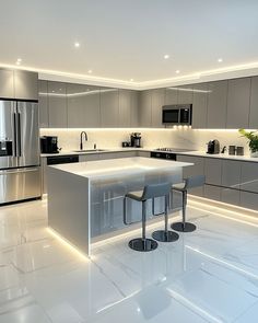 a modern kitchen with stainless steel appliances and white marble countertops, along with two bar stools