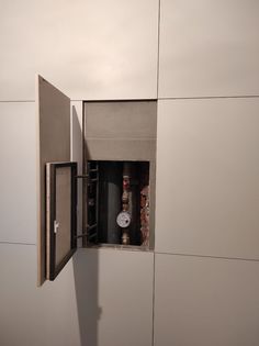 an open door on the side of a wall with bottles in it and a clock