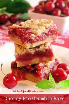 three pieces of cherry pie on a plate with cherries around the edges and green leaves