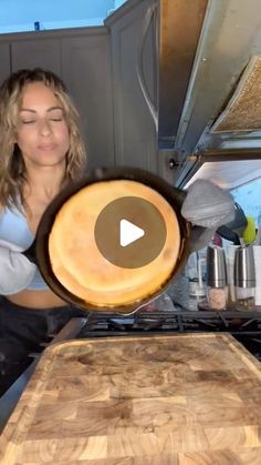 a woman is cooking something in a pan on top of the stove with her eyes closed