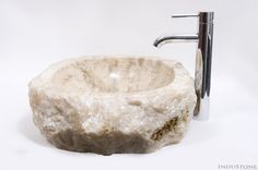 a white marble sink sitting under a faucet next to a metal faucet