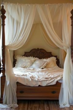 a canopy bed with white drapes and pillows