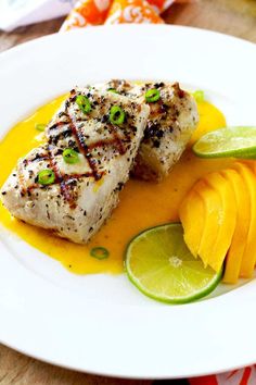 a white plate topped with fish and mango slices