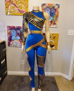 a mannequin dressed in blue and gold is standing next to paintings on the wall