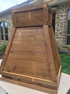 a large wooden box sitting on top of a cement slab in front of a house