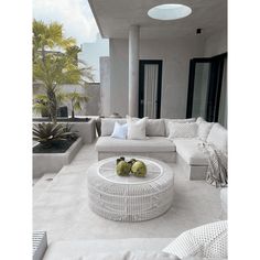 a living room filled with white furniture and plants