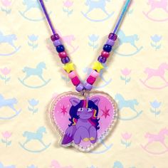 my little pony twilight sparkle charm kandi necklace!! acrylic charm on the necklace is double-sided, with 2 different designs for twilight. both sides have a sparkly holographic. necklace has a tear-away clasp (see photo 3). necklace is about 20 inches long. charm on the necklace is designed by clowshine. if you need a necklace length adjustment, please send me a message. but please be aware i may not be able to make the cord on the necklace the exact same colors as shown in photos. acrylic charms have a clear plastic protective film on the back, which are meant to be peeled off for full visibility of the charm.  shipping is tracked, shipped by USPS! Playful Purple Necklace For Gift, Cute Handmade Purple Necklaces, Playful Purple Necklaces For Gifts, Playful Purple Necklace For Gifts, Holographic Necklace, Mlp Necklaces, Mlp Shirt, My Little Pony Twilight Sparkle, Mlp Star Catcher