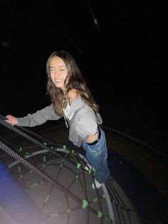 a girl is standing on the edge of a railing at night with her arms outstretched