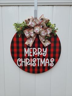 a red and black plaid christmas door hanger with a bow on it that says merry christmas