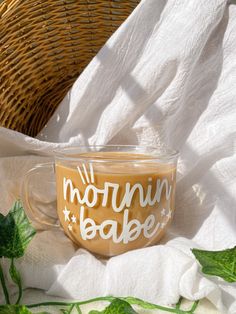 a glass cup with the words morning bake on it sitting next to a wicker basket