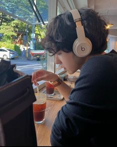 a young man wearing headphones sitting at a table with drinks in front of him