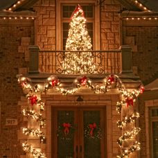 a christmas tree is lit up in front of a house