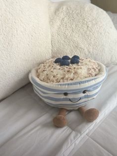 a bowl filled with rice and blueberries sitting on top of a white bed next to pillows