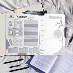 an apple planner and pen on a bed