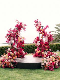 an outdoor ceremony setup with flowers and greenery on the lawn by the ocean in front of it