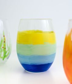 three different colored vases sitting next to each other on a white surface with water in them