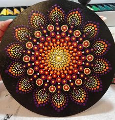 a person holding up a black plate with orange and purple designs on the inside of it