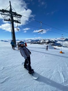 a person riding a snowboard on top of a snow covered slope next to a ski lift