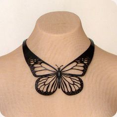 a black butterfly necklace on a mannequin neckline, with the wings open