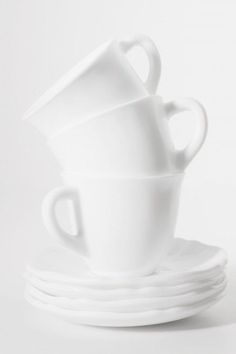 three white cups and saucers stacked on top of each other