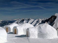 an igloose on top of a snowy mountain with mountains in the background