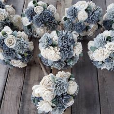 several bouquets of flowers are arranged on a wooden table with grey and white colors