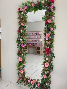 a mirror that has flowers on it in front of a white wall and tiled floor