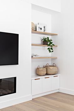 a flat screen tv mounted on top of a white wall next to a fire place