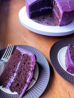 a slice of purple cake on two plates with a fork next to it and another piece missing from the cake