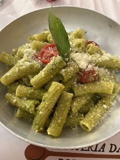 a white bowl filled with pasta covered in pesto