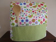 a wooden spoon sitting on top of a green and white flowered bag with polka dots