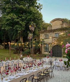 an outdoor dining area with tables and chairs set up for a formal dinner in the garden