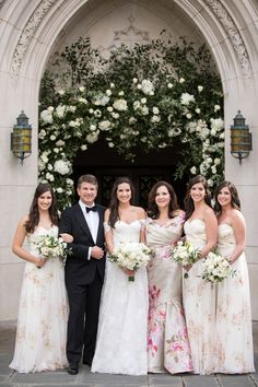 a group of people standing next to each other in front of a building with flowers