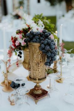 a table topped with a vase filled with lots of grapes