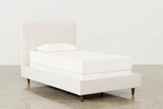 an upholstered bed with white sheets and pillows