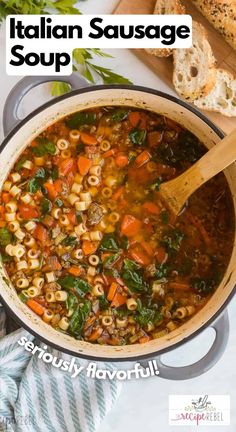 italian sausage soup in a large pot with a wooden spoon and bread on the side