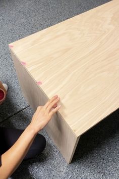 a person kneeling down next to a wooden table