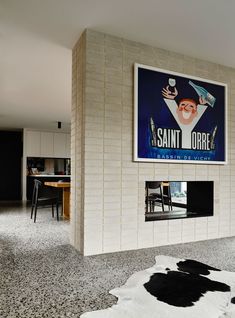 a black and white cow rug in front of a brick wall with a poster on it