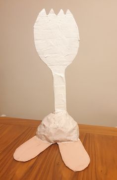 a white paper mache sitting on top of a wooden table next to a wall