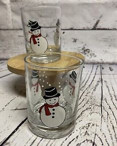 two glass tumblers with snowmen on them sitting next to each other in front of a