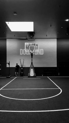 an indoor basketball court with two men on the sidelines